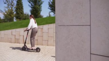 Bir kadın parkta elektrikli scooter kullanır. Trafik sıkışıklığı olmadan şehir etrafında hızlı hareket için yeni gadget