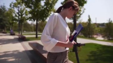 Bir iş elbisesi ve elinde bir klasör genç güzel kadın iş tatilinde bir park bankında oturur