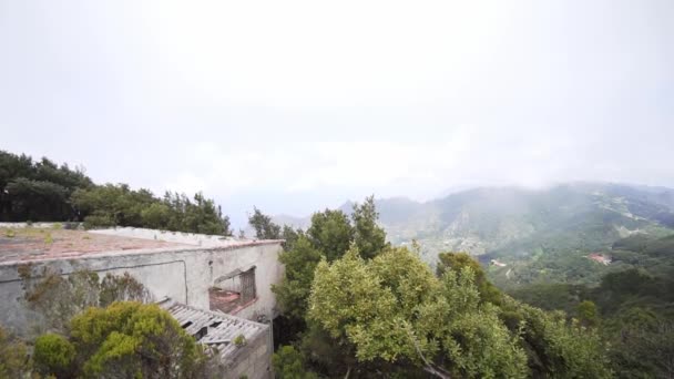 Een geruïneerd gebouw in een vulkanisch gebied hoog in de bergen, te midden van een groene vallei en een bergketen. Natuurlijk landschap op een zonnige lentedag — Stockvideo