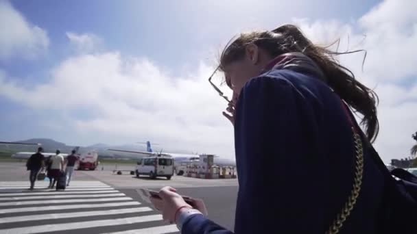 Turista femenina abordando un avión cerca del aeropuerto. Chica con una mochila de salida en unas vacaciones, vista trasera — Vídeos de Stock