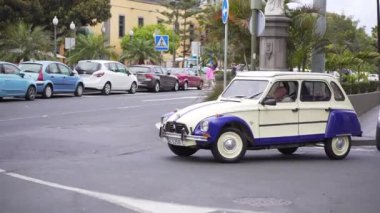 Las Palmas de Gran Canaria, İspanya - Nisan 23, 2019 - Yaşlı bir adam şehir trafiğinde güzel bir retro araba sürmek. Beyaz-mavi eski araç, bir Avrupa şehrinin sokakta hareket eden bir emekli