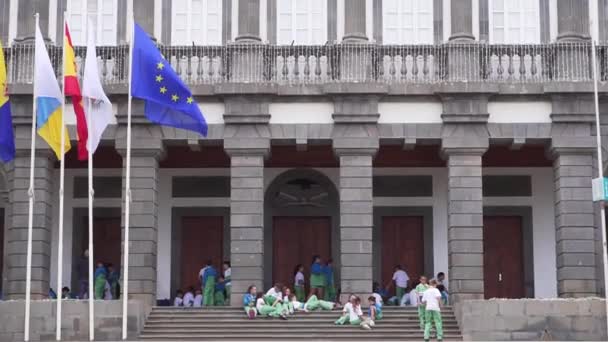 Лас-Пальмас-де-Гран-Канария, Испания - 23 апреля 2019 года - школьники во время перерыва, рядом с правительственным зданием. Флаги Испании и Европы трепещут на ветру — стоковое видео
