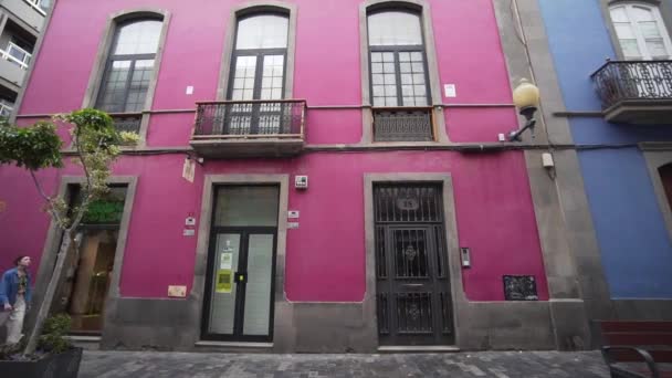 Een jonge vrouw heeft plezier en loopt langs een prachtig roze gebouw in een kleurrijke Spaanse stad. Groothoek. Avontuur op vakantie, wandelen langs de straten. — Stockvideo