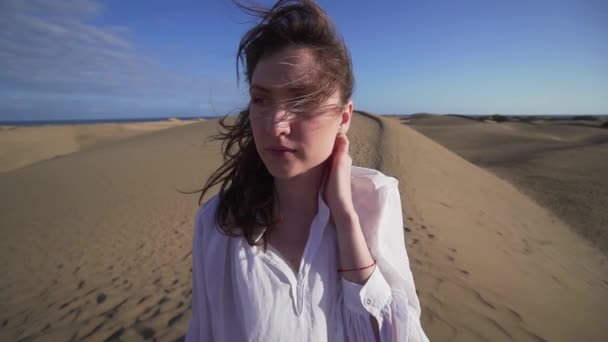 Una giovane donna è in piedi nel vento in un deserto caldo, i suoi capelli si muovono . — Video Stock