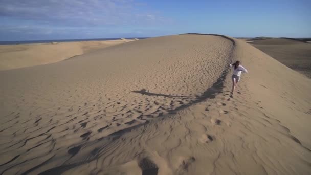 Eine Frau in der Wüste genießt ihren Urlaub, lächelt und rennt den Sand hinauf. — Stockvideo