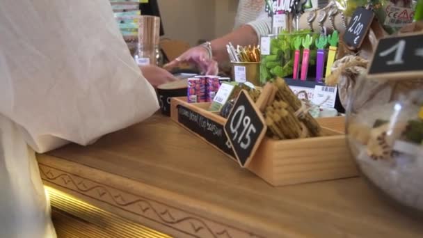 Une acheteuse paie les marchandises dans une boutique de cadeaux à l'aide d'un terminal et d'une carte de crédit. Fermer, souvenirs de vacances, transaction par carte de crédit — Video