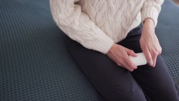 Ziekteseizoen - een jonge vrouw wordt thuis behandeld, opent een pakket van koude geneeskunde zittend op het bed. Statisch close-up schot — Stockvideo