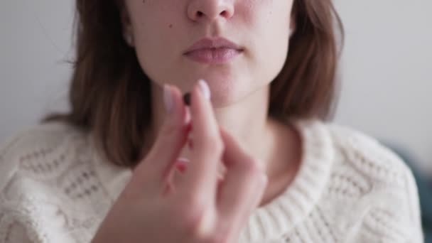 一个年轻的女人把一片安眠药放进嘴里，喝了一杯水。 益生菌和矿物质片，一种在疾病季节保持免疫力的有效药物，特写 — 图库视频影像