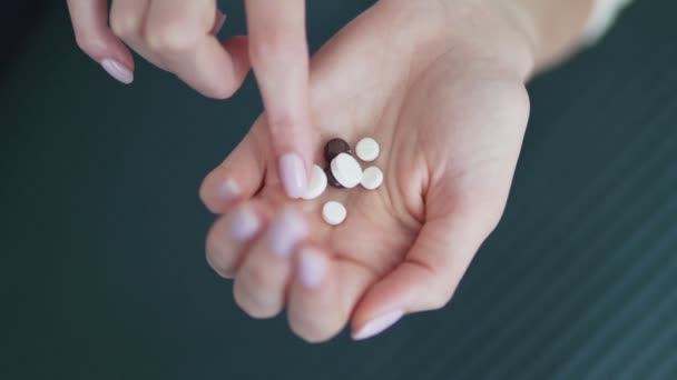 Органические и природные лекарства. Таблетки в руке молодой женщины. Женьшень, кальций, витамины и минералы в руке — стоковое видео