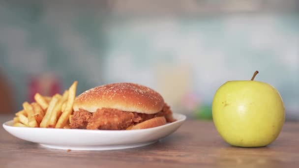 Papas fritas con hamburguesa contra manzana verde jugosa. Fuerza de voluntad al elegir un aperitivo — Vídeos de Stock