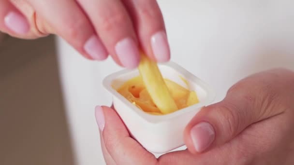 Patatine fritte tuffo in salsa. Fast food nelle mani delle donne primo piano. Obesità e malessere — Video Stock