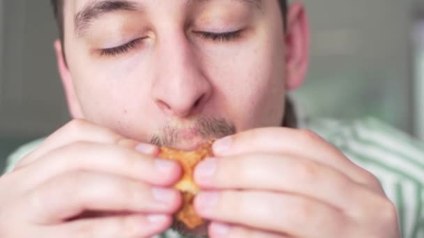 Ein Mann beißt einen ungesunden Hamburger. Männlich mund close-up, hungrig mann dines im büro — Stockvideo