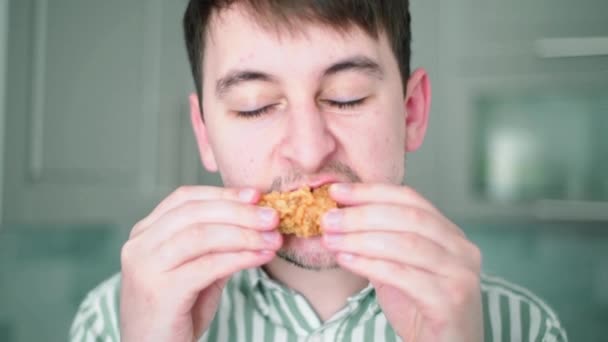 Ein Mann beißt in einen Hühnerflügel. Überernährung und Übergewicht. Schädliches Fast Food — Stockvideo