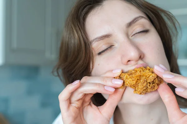 不健康的暴饮暴食一个女人咬鸡块，特写。垃圾食品 — 图库照片