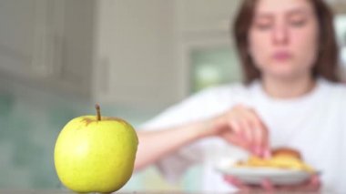 Sağlıksız yemek seçenekleri. Yanlış beslenme ve aşırı yeme. Kadın elmaya karşı çizburger ve patates kızartması yiyor.