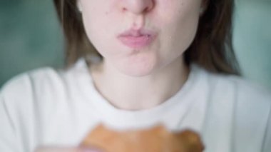 Kontrolsüz aşırı yeme. Bir kadın çizburger yiyor. Bir kızın ellerinde etli hamburger.