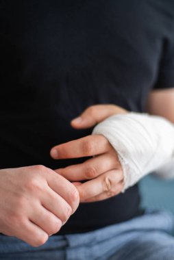Sağlıklı bir genç adam alçıtaşında kırık bir kola masaj yapıyor. Kırığın ardından yaralanan kolun iyileşmesi.