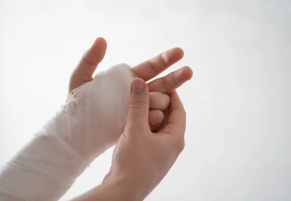 Aqueça os dedos dos jovens homens braço quebrado close-up contra um fundo branco. Braço quebrado em gesso branco faz fisioterapia — Fotografia de Stock