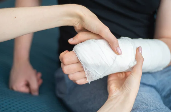 Apoio e cuidados para o paciente com um braço quebrado. A mão está em gesso. Reabilitação após lesão, fisioterapia — Fotografia de Stock