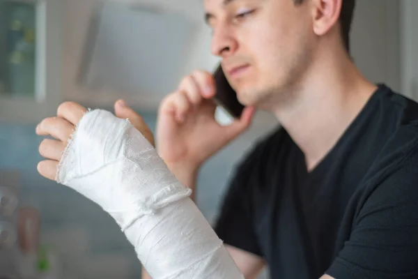 A pessoa com a mão partida fala ao telefone. Trabalhar como freelancer durante uma licença médica — Fotografia de Stock