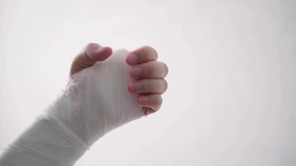 Calienta los dedos del brazo roto de los jóvenes sobre un fondo blanco. Brazo roto en yeso blanco hace fisioterapia — Vídeos de Stock
