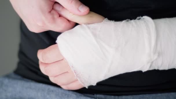 Rehabilitace po zlomené ruce. Muž si masíruje ruku sádrou, zblízka. — Stock video