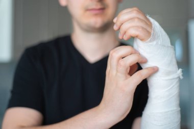 Bandajın altında kaşıntı var. Kırık kolu tırmalamaya çalışan adam, yakın plan.