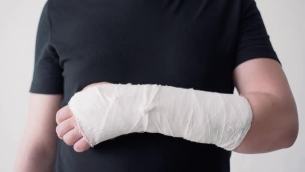 En bruten hand i ett gipsbandage. Han försöker böja fingrarna. Smärtsamma tunga rörelser av brutna fingrar närbild — Stockvideo