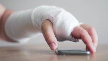 Kırık bir kişi telefona cevap vermek için telefonu almaya çalışıyor. Yaralanmaktan rahatsız, kolumda ağrı var.