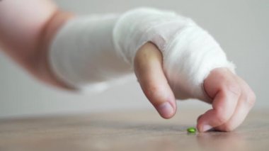 Bandajdaki kırık el ağrı kesici almaya çalışıyor. Yaralandıktan sonra stres ve acı.