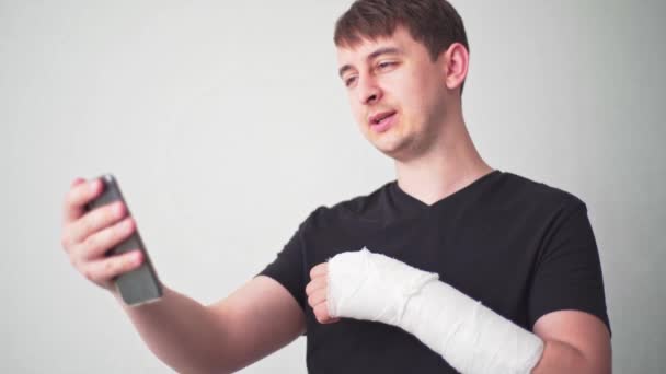Телемедицина. Зламана рука. Пацієнт з переломом кісток спілкується на відеозв'язку з лікарем і показує гіпс — стокове відео