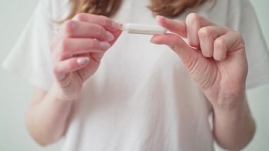 Beyaz bir arka planda kadın eli olan bir tampon. Regl dönemindeyiz. Adet sırasında koruma