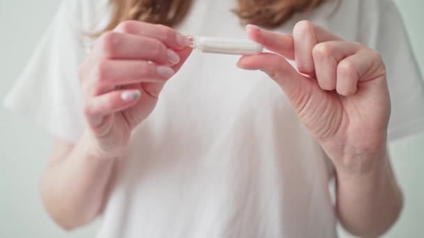 Un tampon dans les mains des femmes sur un fond blanc. Période de règles. Protection pendant les règles — Video