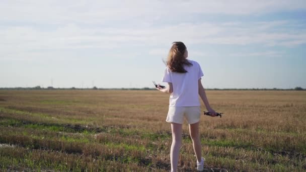 La piloto del avión no tripulado entra en el campo e inspecciona antes del vuelo. Drone en las manos de las mujeres — Vídeo de stock