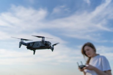 Kadın bir pilot. Gün batımında güzel gökyüzüne karşı dronu kontrol et. Yerin üstünde uçuyor
