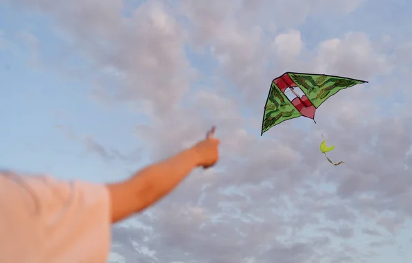 Kite is flying. Hand holds flying kite at sunset, amid beautiful clouds