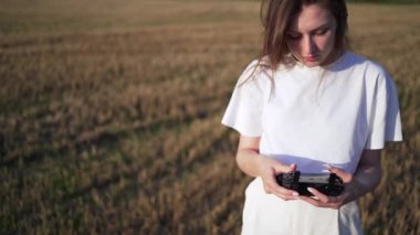 Tarladaki genç ve güzel bir kadın uçarken bir dronu kontrol ediyor. Uzaktan kumanda ile İHA 'yı kontrol et