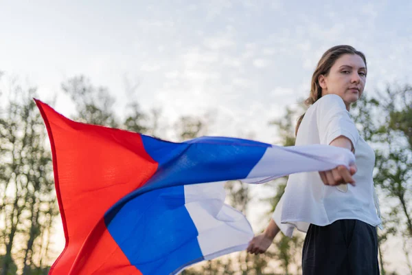 Uma mulher corre com a bandeira russa nas mãos. O símbolo da Rússia acenando lindamente nas mãos de uma mulher — Fotografia de Stock