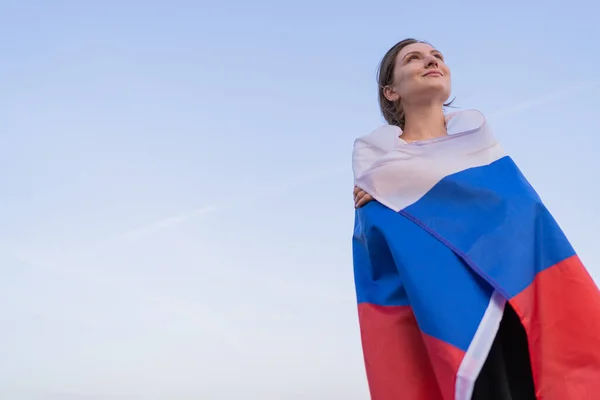 Mulher patriota. Uma bela mulher russa com a bandeira da Federação Russa olha para o futuro contra o céu brilhante ao pôr-do-sol. Um lugar para o seu texto — Fotografia de Stock