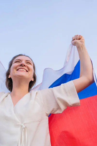 Woman with the Russian flag celebrating the victory in the competition. Excited Russian cute woman against the sky