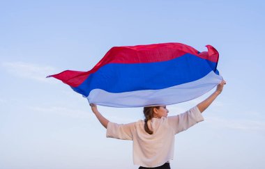 Rusya bayrağı taşıyan bir kadın doğada koşar. Mutluluk ve vatanseverlik, Rusya Federasyonu bayrağı sallama