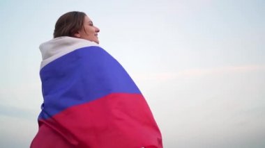 Bir kadın omuzlarına bir Rus bayrağı atar ve uzaklara bakar. Rusya 'da Bağımsızlık Günü