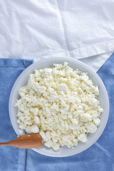 Bir beyaz mavi kumaş arka plan, beyaz bir plaka üzerinde yumuşak peynir, taze ev yapımı peynir beyaz mavi peçeteye süzme peynir. Süt ürünleri vintage tarzı, sağlıklı bir yaşam tarzı. Kopya alanı