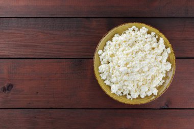 Süzme peynir peynir sarı bir plaka üzerinde ahşap kurullarında. Süt ürünleri üzerinde kahverengi ahşap arka plan, sağlıklı bir yaşam tarzı. Kopya alanı