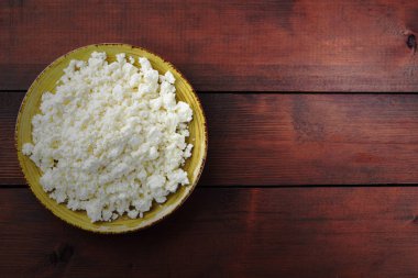 Süzme peynir peynir sarı bir plaka üzerinde ahşap kurullarında. Süt ürünleri üzerinde kahverengi ahşap arka plan, sağlıklı bir yaşam tarzı. Kopya alanı