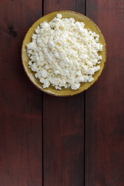 Süzme peynir peynir sarı bir plaka üzerinde ahşap kurullarında. Süt ürünleri üzerinde kahverengi ahşap arka plan, sağlıklı bir yaşam tarzı. Kopya alanı