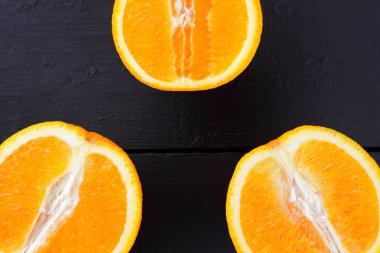 Meyve portakal portakal ahşap kurullarında yarısı siyah ahşap zemin. Uzay kopyalayın. Vejetaryen kahvaltı için narenciye