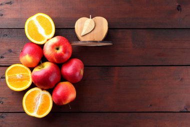 Meyve portakal ve kırmızı elma portakal ahşap kurullarında yarısı bir koyu kahverengi ahşap zemin üzerinde. Uzay kopyalayın. Narenciye ve vejetaryen kahvaltı için elma