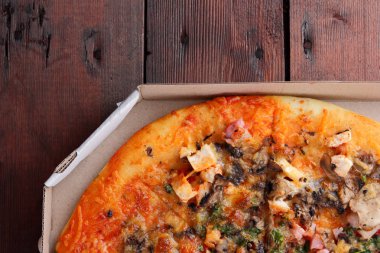 Pizza ahşap arka plan üzerinde bir kutu içinde. Tavuk, mantar, yeşillik, peynir ve sos İtalyan pizza. Festival yemek bir karton kutu içinde. Kopya alanı