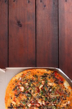 Pizza ahşap arka plan üzerinde bir kutu içinde. Tavuk, mantar, yeşillik, peynir ve sos İtalyan pizza. Festival yemek bir karton kutu içinde. Kopya alanı